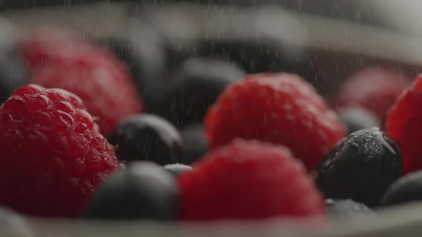 Water is spraying on the blueberries and raspberries