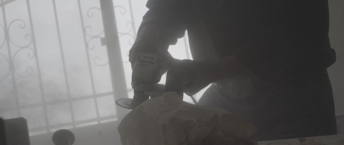 A man is using a tool to carve stone
