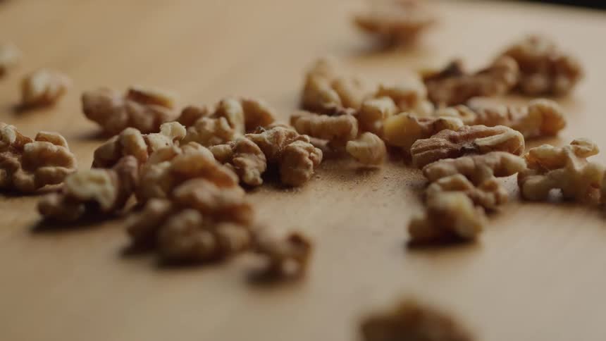 A series of walnuts are poured out onto a wooden surface