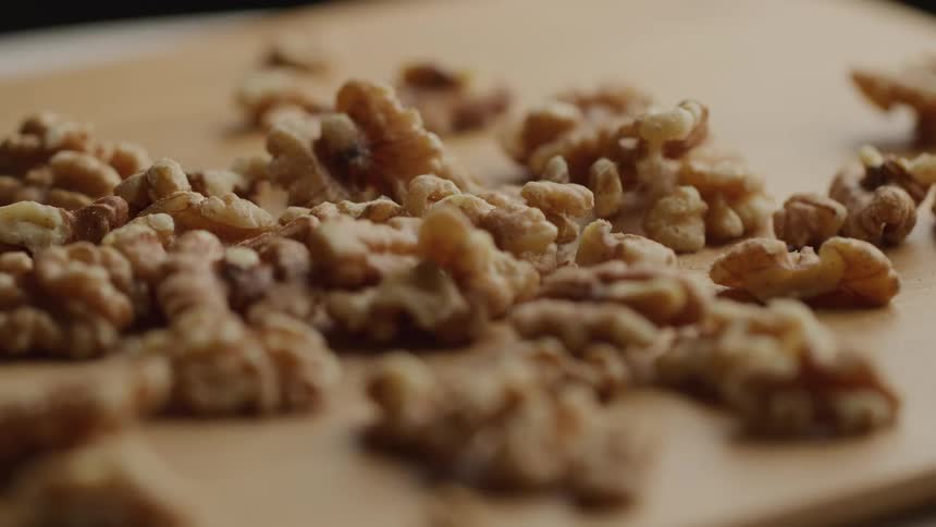 Walnuts scattered across a wooden board in closeup