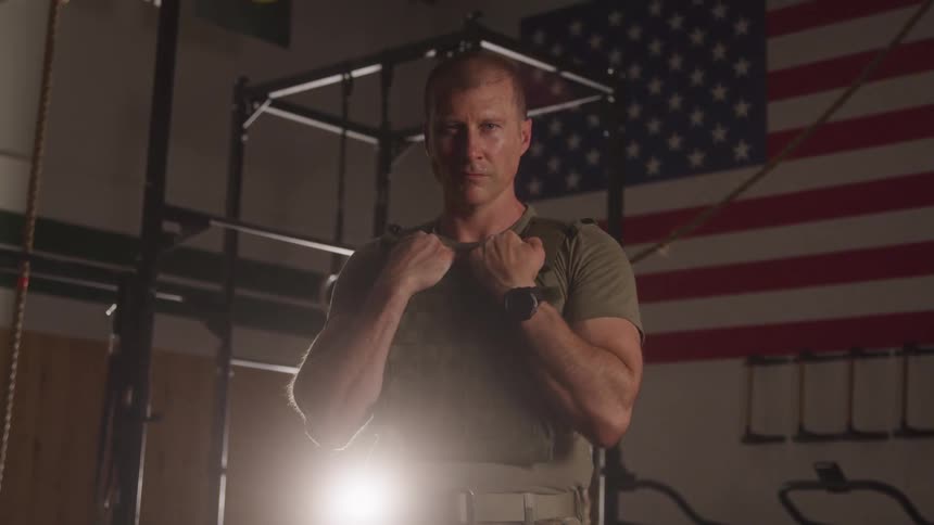 The soldier is wearing a bullet proof vest in the gym