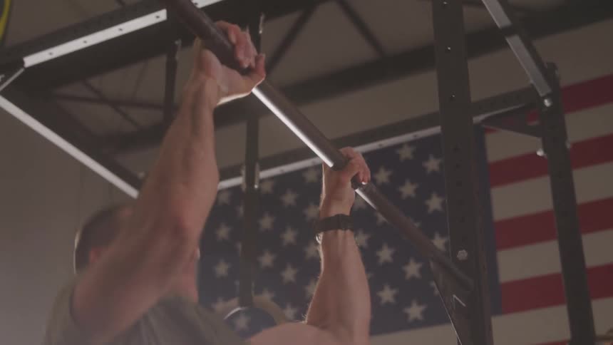 Military man in an indoor space doing pullups