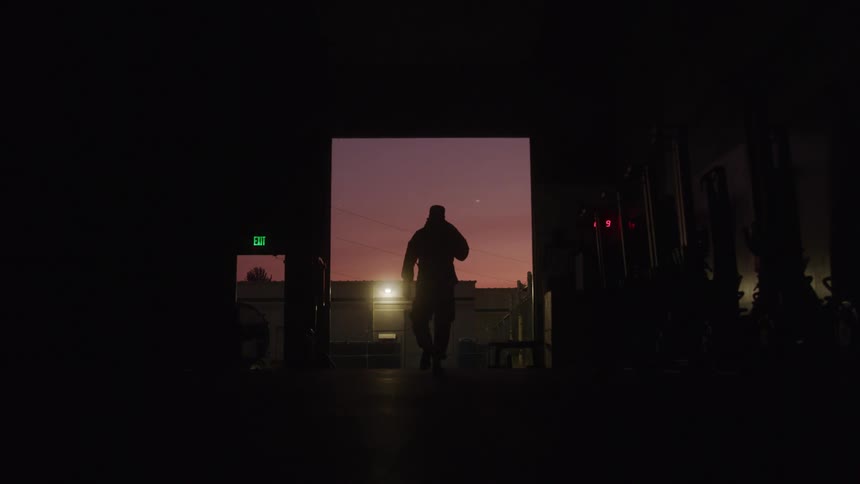 Person walks toward a gym exit as the sky glows pink at dusk