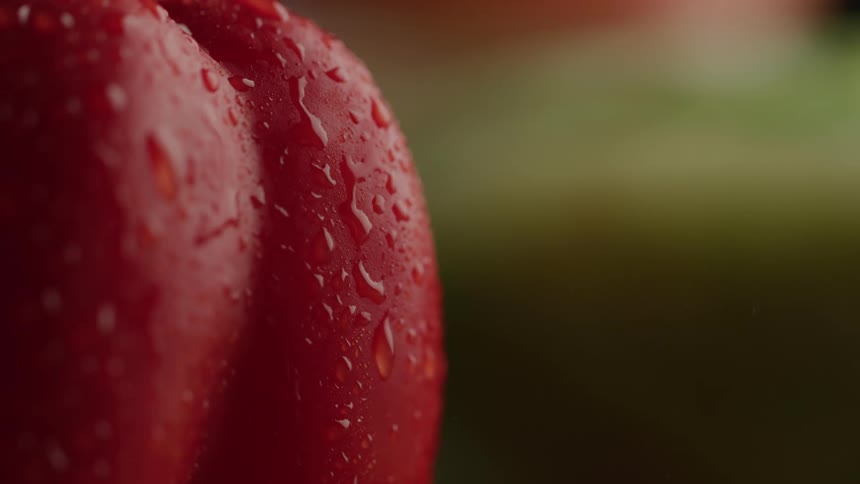 Extreme close of water droplets dripping off a wet red bell pepper