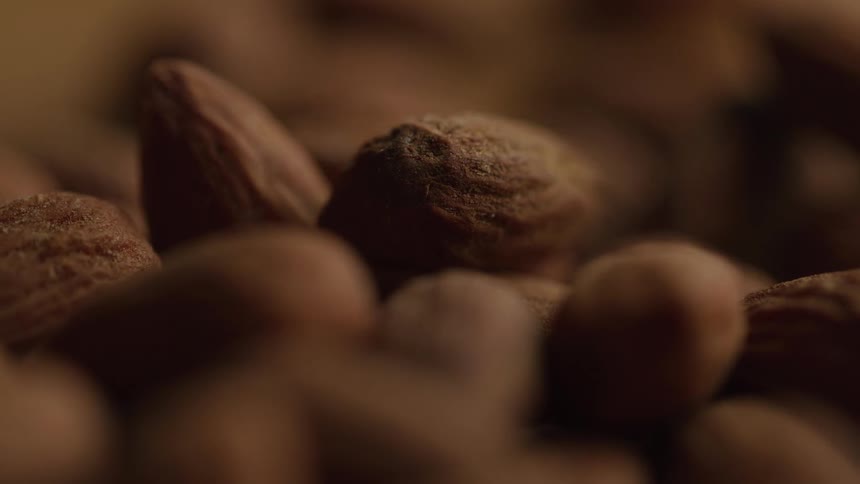 A close view shows a heap of dark brown almonds
