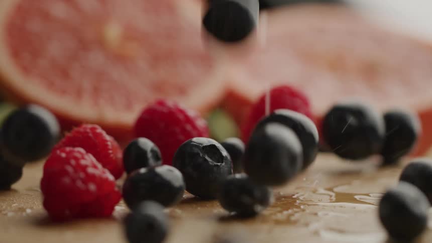 Closeup shot of berries on a wet board with grapefruit behind