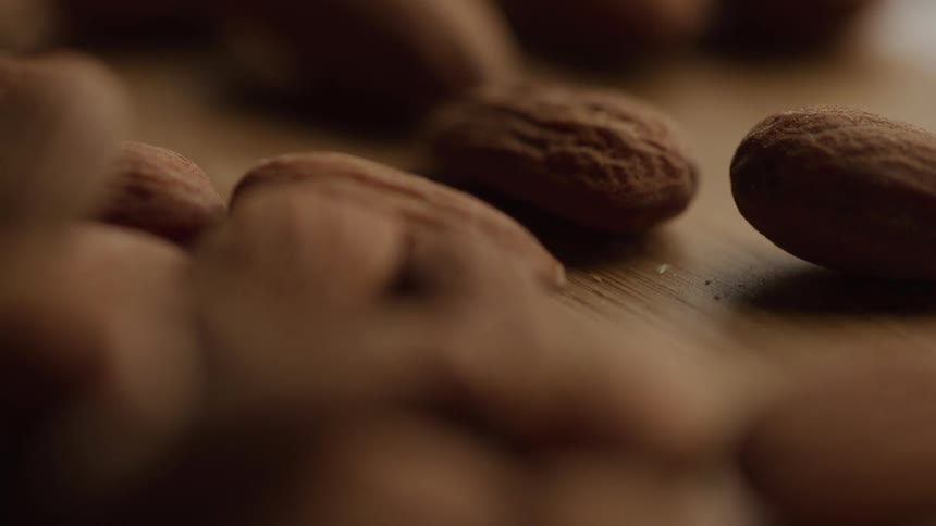 Closeup shot of raw almonds scattered on a wooden table