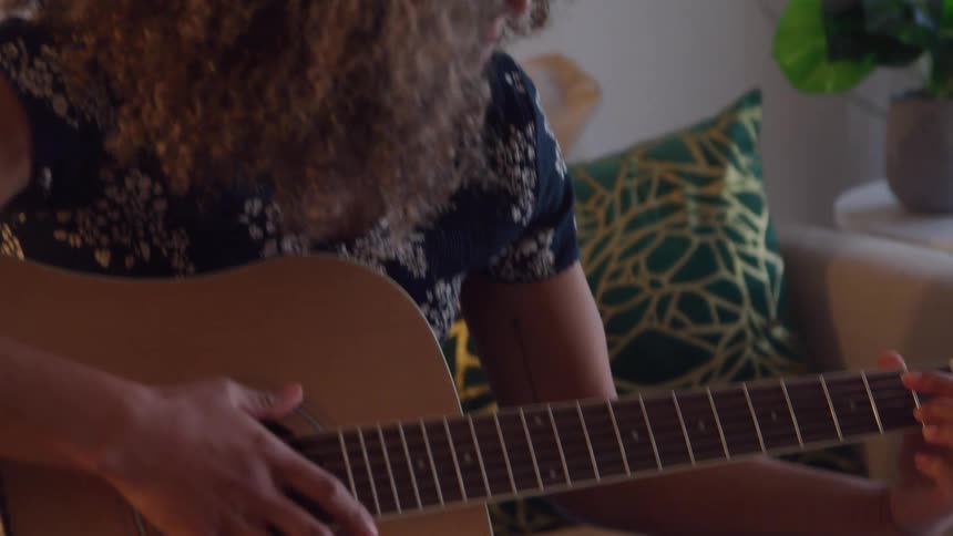 Woman sitting on the sofa playing guitar