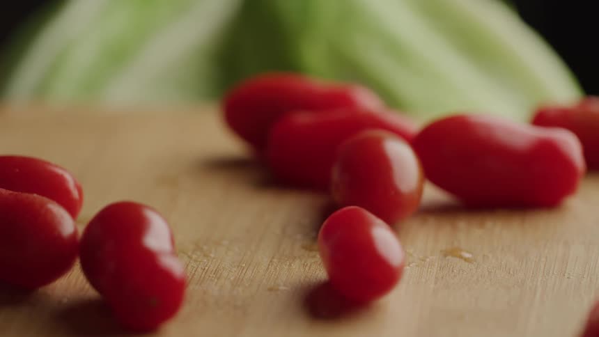 Dropping red grape tomatoes on a wooden cutting board