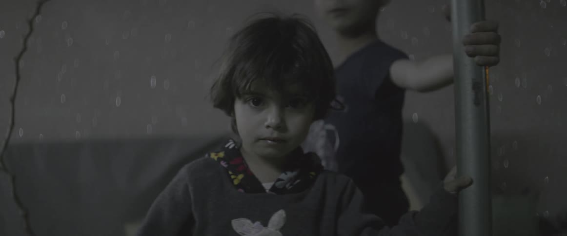 Two children hold onto a metal pole in a room