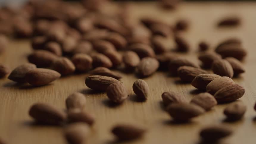 Hazelnuts are poured onto a wooden surface causing them to scatter across the floor