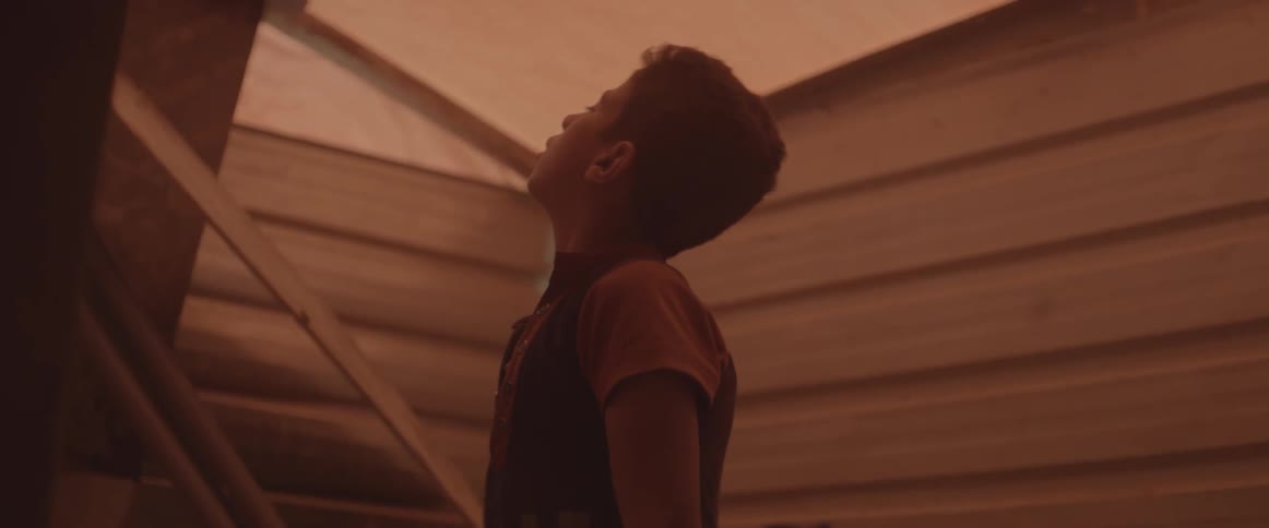 A boy is looking up at the ceiling of the shelter he is in