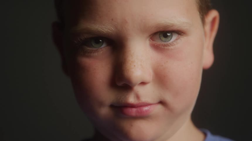The video shows a closeup of a young boys face looking directly at the camera he has lightcolored hair and striking green eyes his expression is neutral a watermark that says filmsupply is visible across the center of the frame