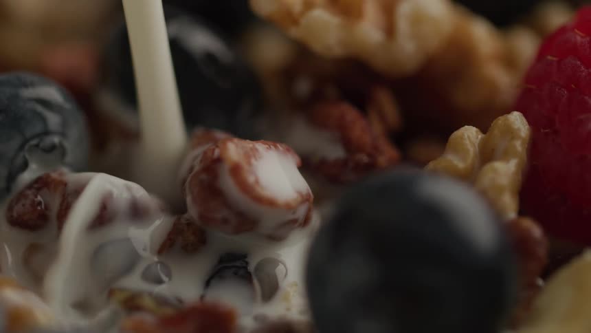 Extreme close up milk pouring over granola and berries