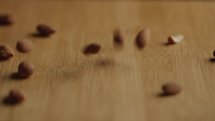 Handful of almonds dropping on to wood counter