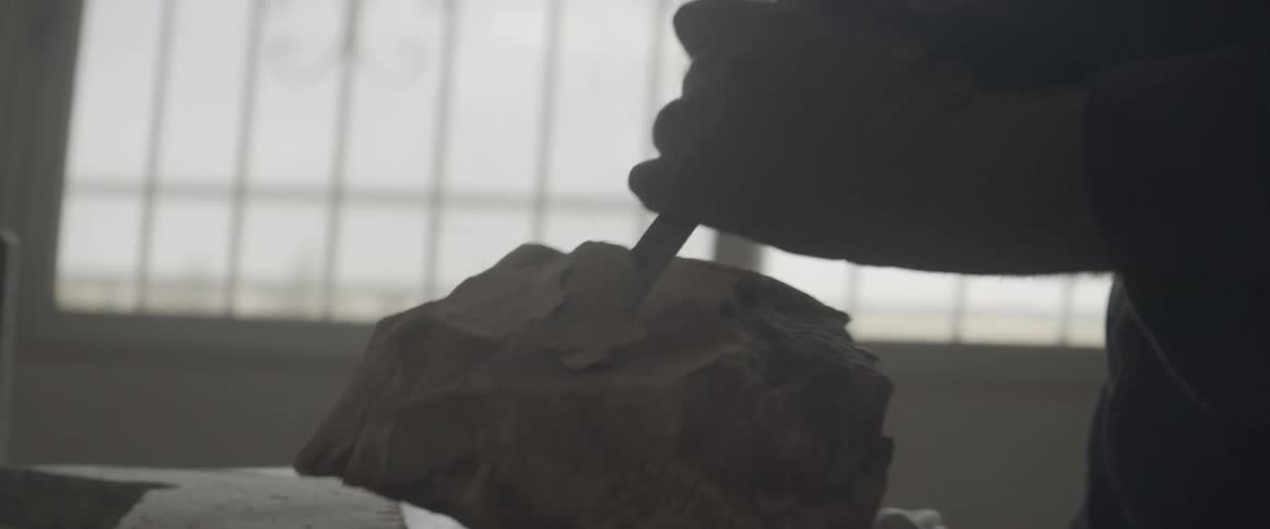 An artist is using a chisel to sculpt a stone