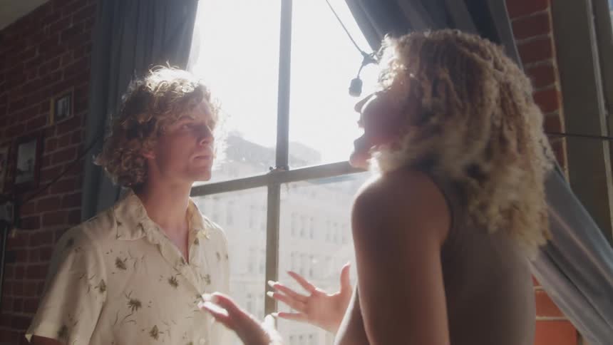 Woman and a man in a room of the house next to the window arguing