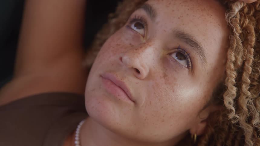 Close up portrait of a young woman lying contemplatively indoors