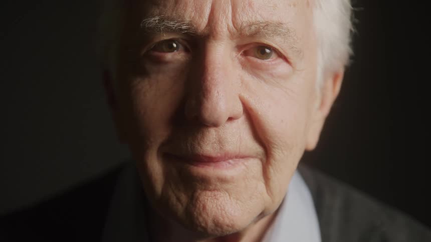 Elderly man smiles gently looking into camera