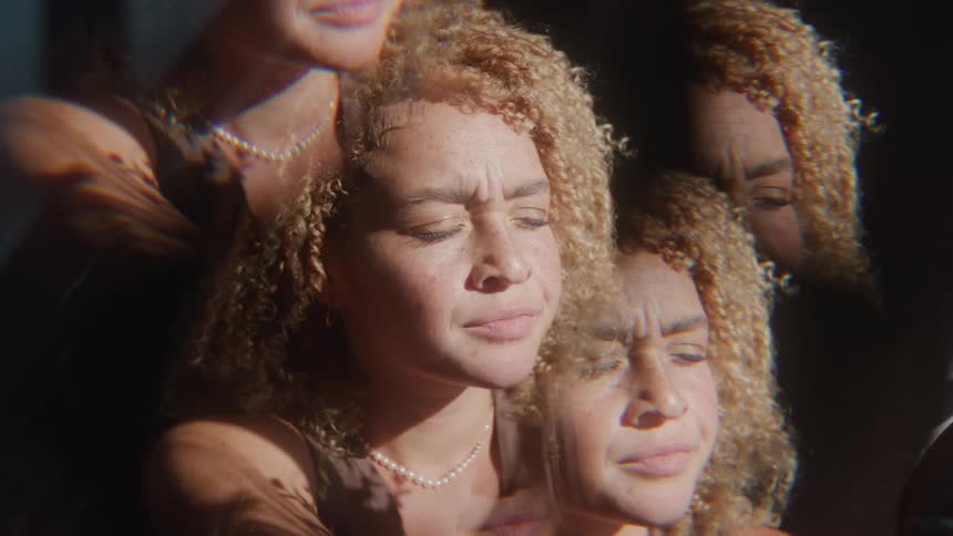 A teenage girl with long curly hair looking sad