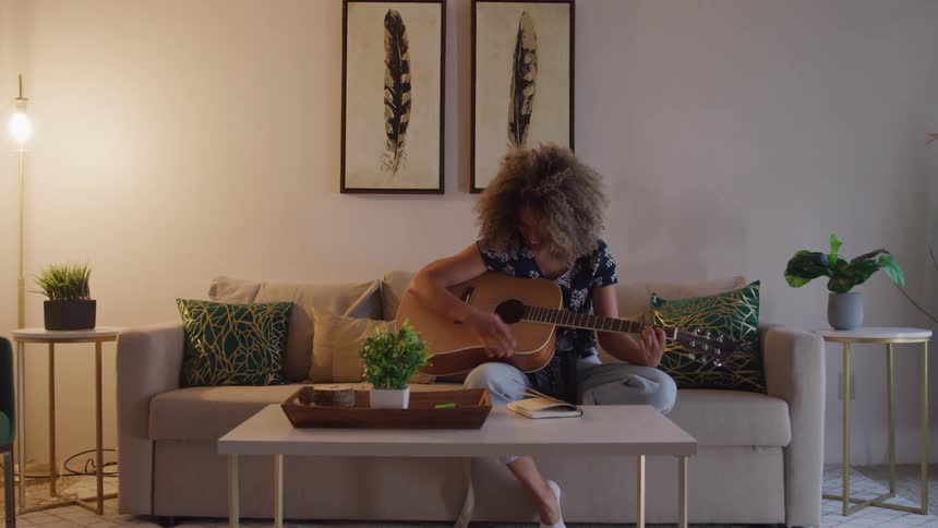 Girl writing in a notebook with a guitar in her hand
