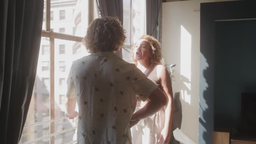 Man and a woman arguing by a window