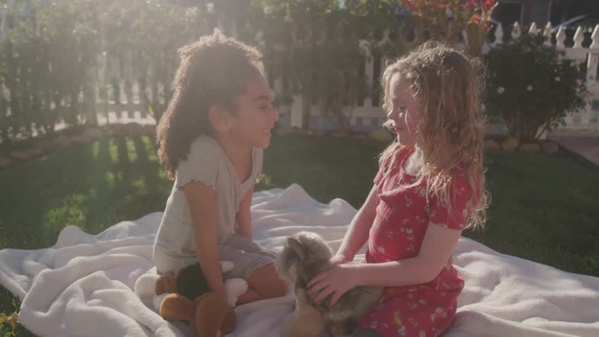 Two friends sit together in the yard with stuffed animals