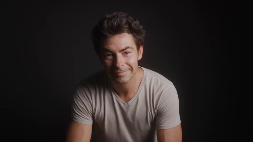 The man is leaning forward and smiling