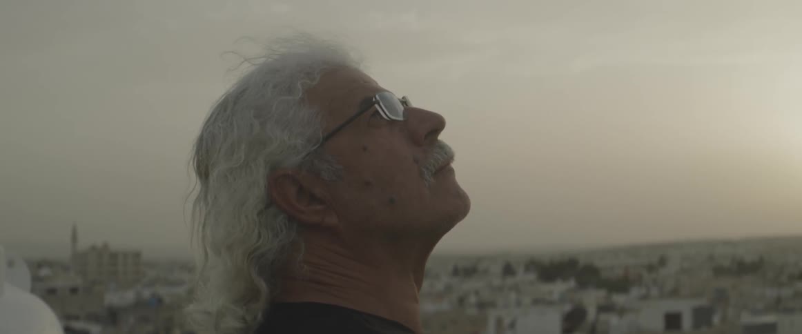 An older man gazes up at the sky at dawn or dusk