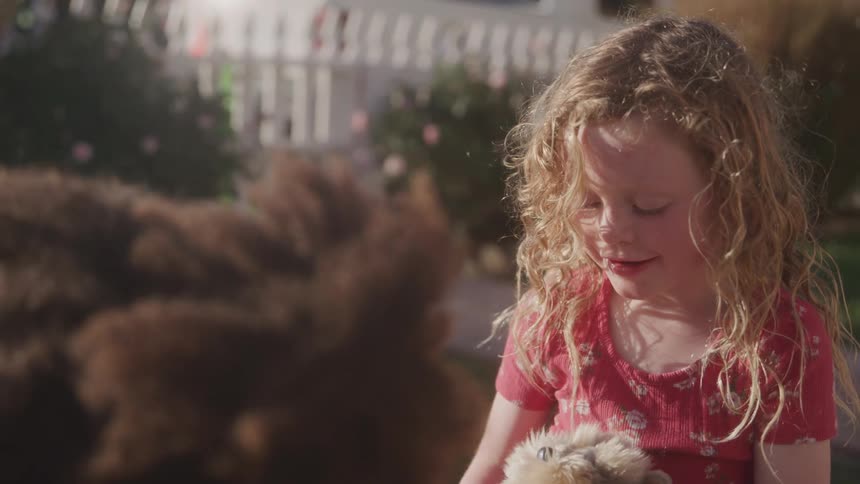 Little blonde girl holding an animal in her hands