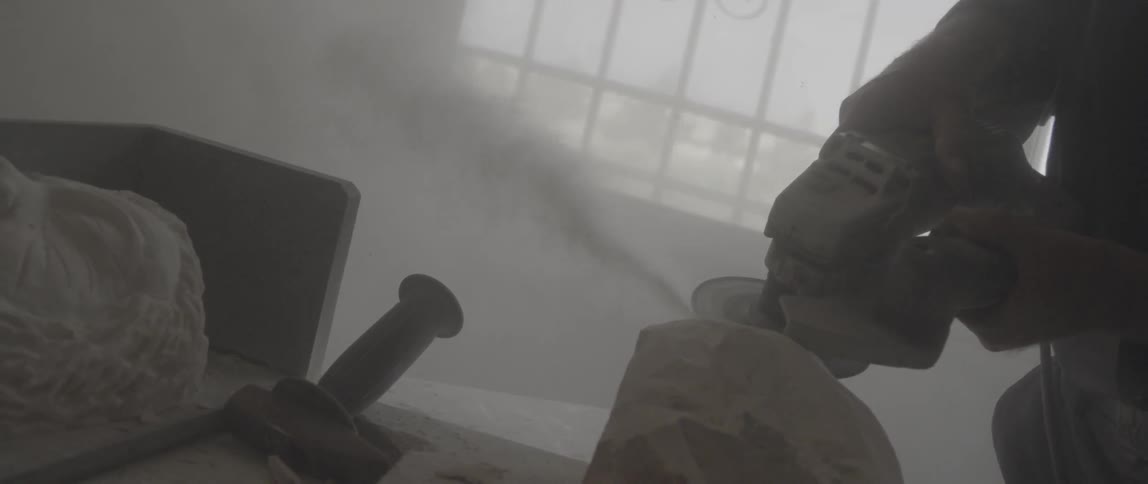 A person is using a large sander to carve stone