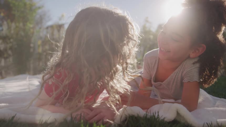 Two little girls playing on a lawn and having fun