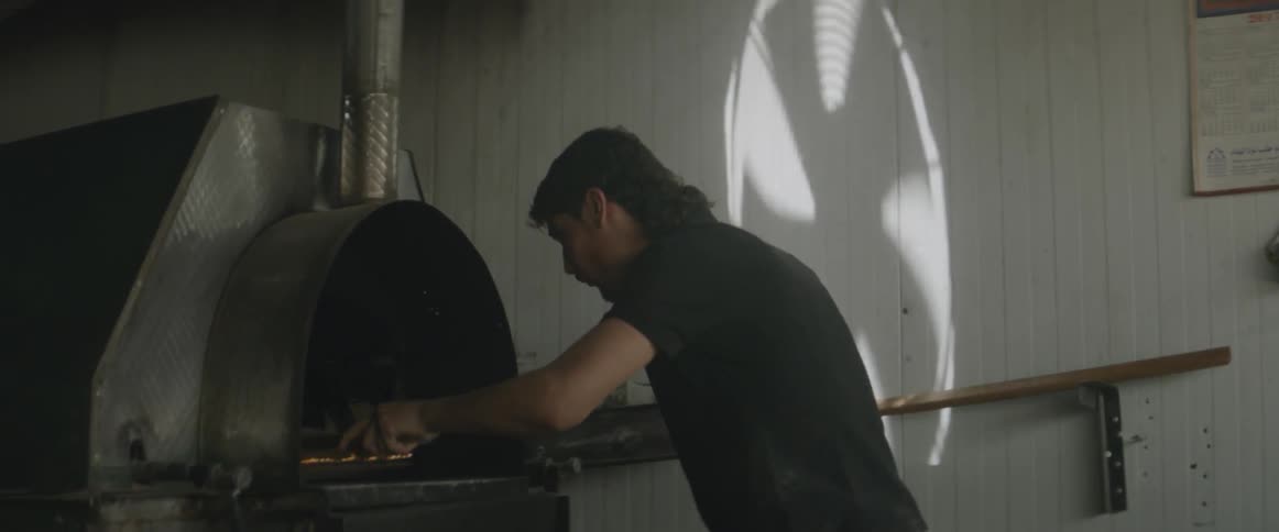 A man pulling a mop in and out of a thing that looks like a big stove