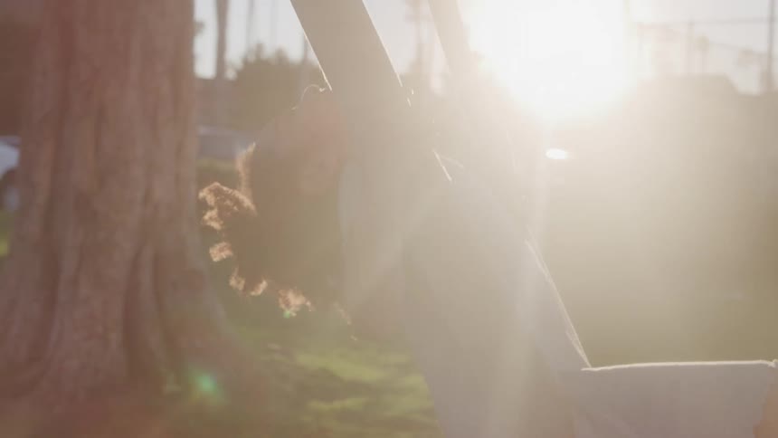 Child plays on a swing outdoors during sunset