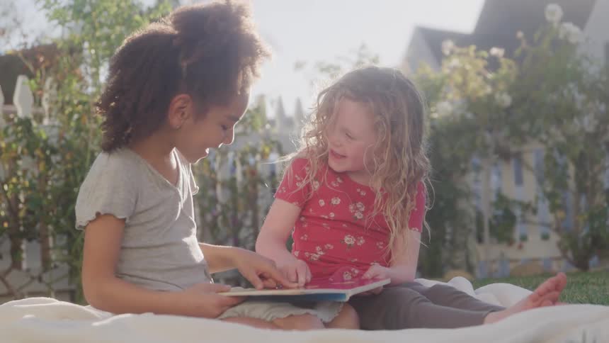 Two little girls sitting reading books