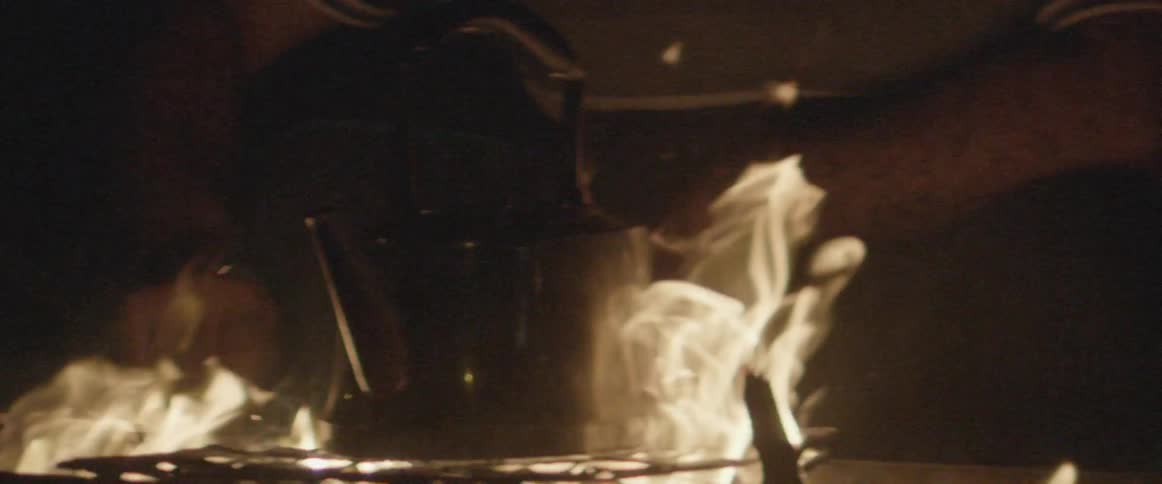 Flames rise up and around a kettle on a fire