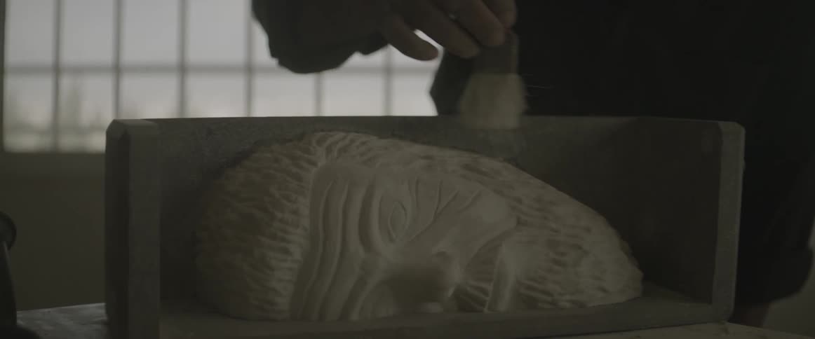 A man brushes dust off a sculpture