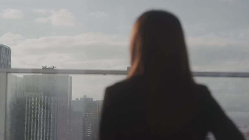 Woman in blazer enjoying panoramic view of buildings and sea in the background