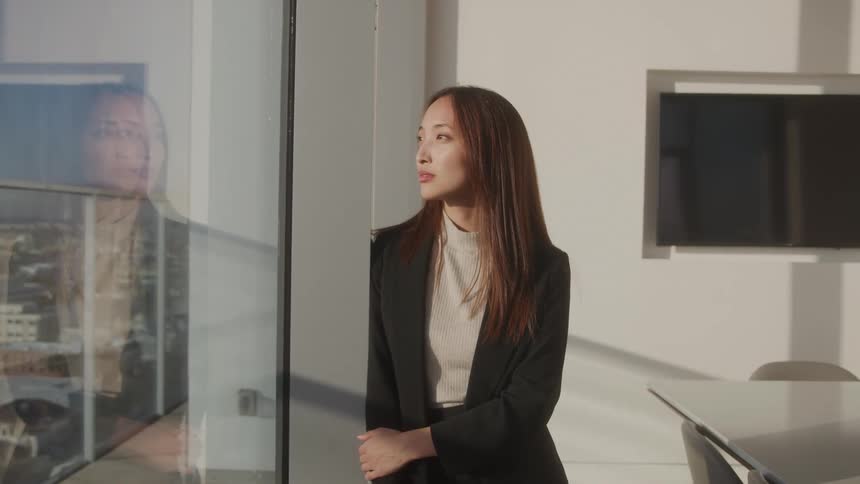 The woman is looking out the conference room window