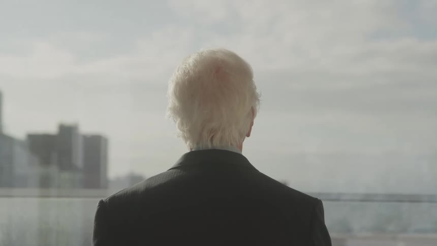 Elderly man in blazer enjoying the sea view on the edge of a metropolis