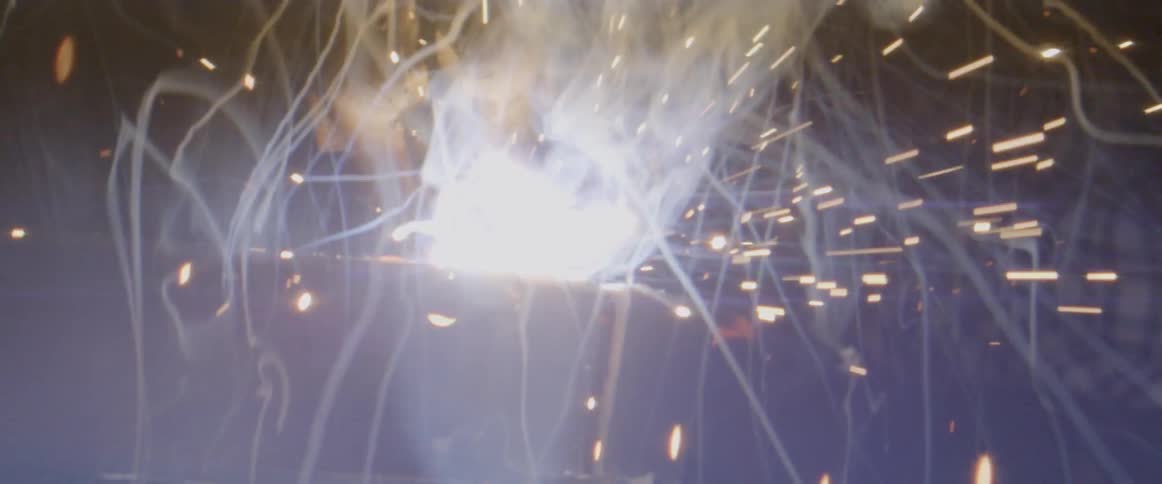 Sparks and smoke lift into the air as a man welds
