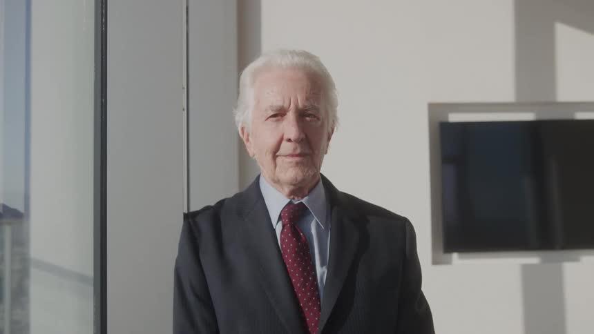 Elderly man in a suit and red tie in an office environment