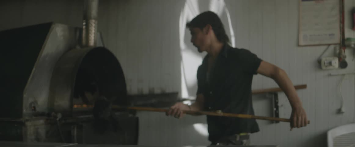 A man puts pizzas into a pizza oven
