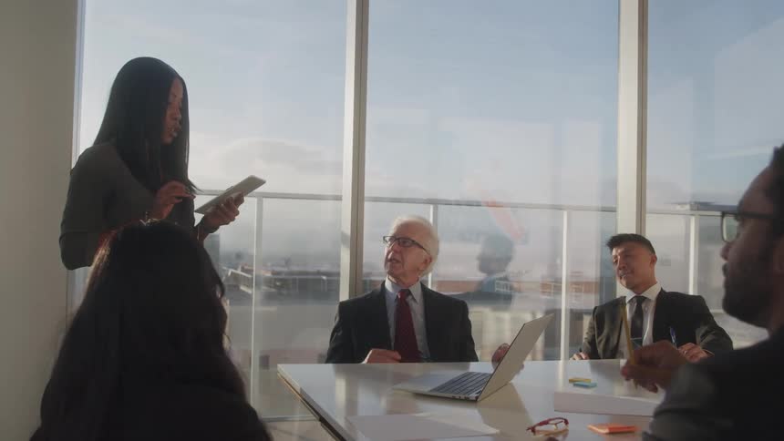 A businesswoman presents to colleagues during a meeting in a modern office