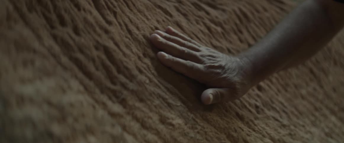 A hand touches a rock wall