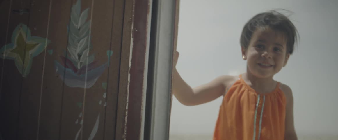 Young girl smiling as she peeks around a corner
