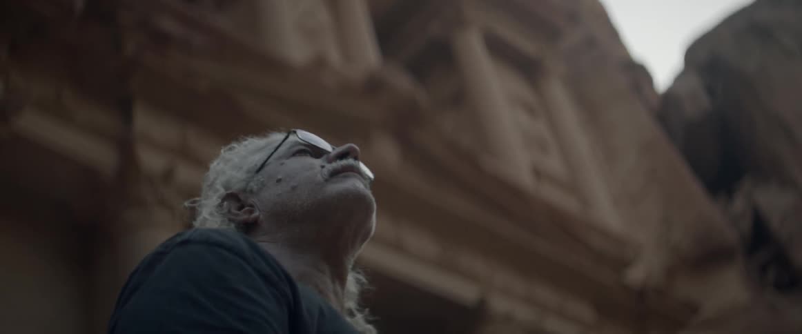 A man looks up and around at the ruins