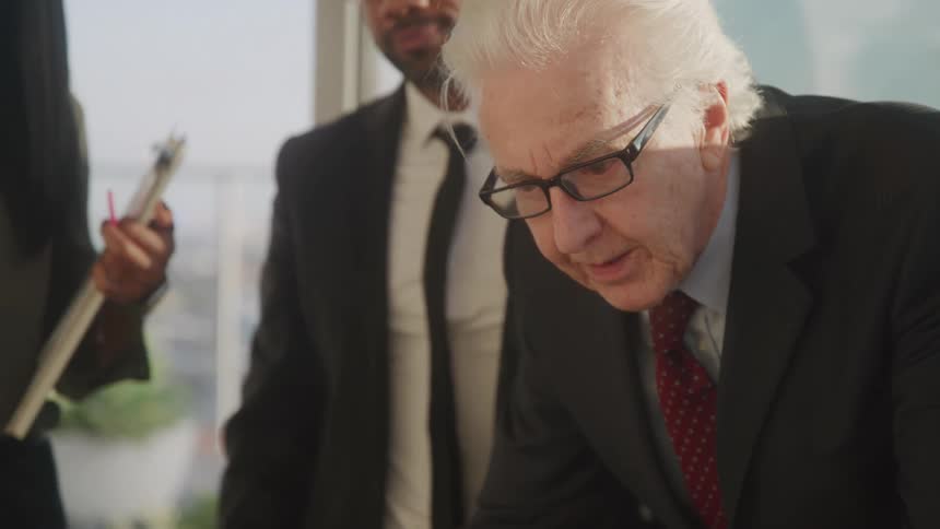 A gentleman putting on his glasses during a business meeting
