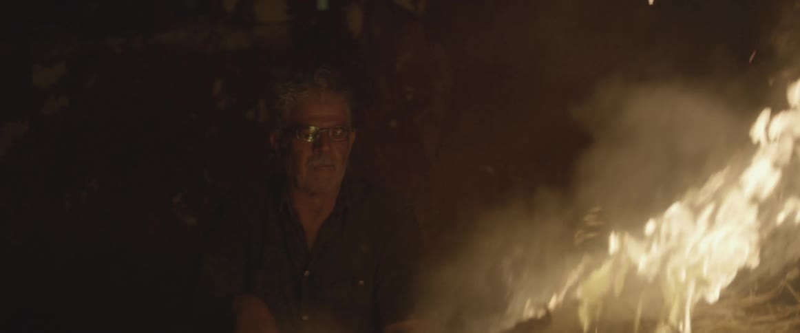 A man is watching a burning fire at night