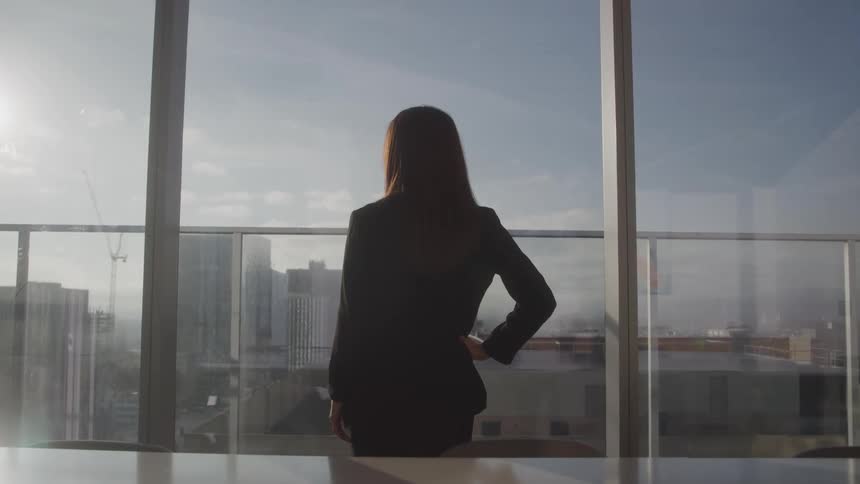 The woman is in the office looking out the window